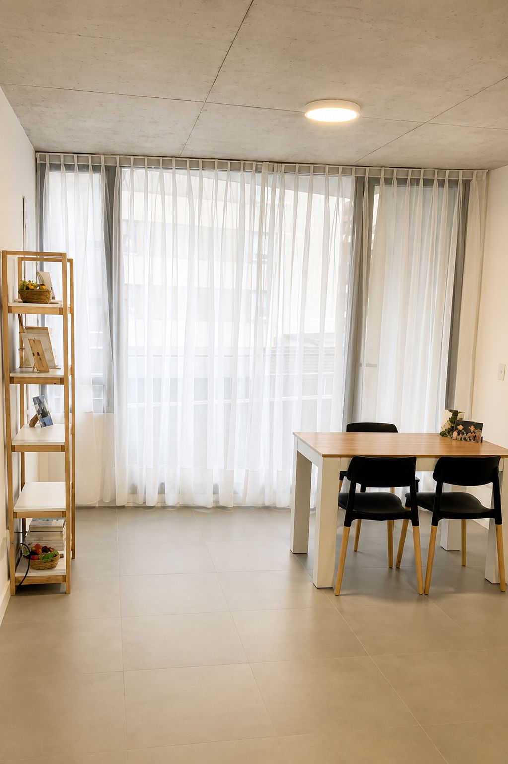 Consultorio de Belgrano: mesa de madera con sillas, ventanal con cortinas y una estantería con portarretratos